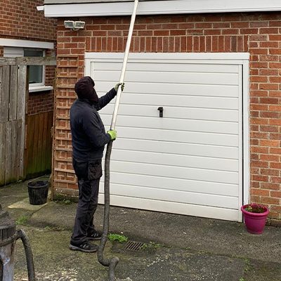 An image of a man using a gutter cleaning vacuum cleaner